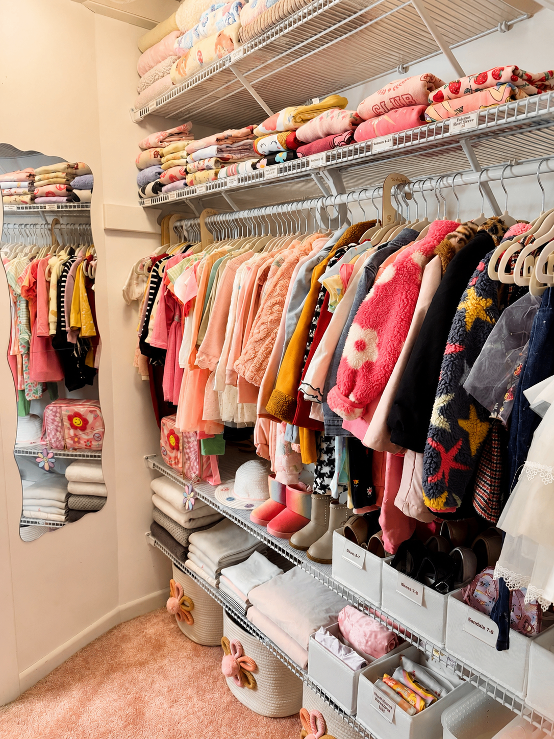 Children's closet with pink clothing, shoes, and organized baskets.