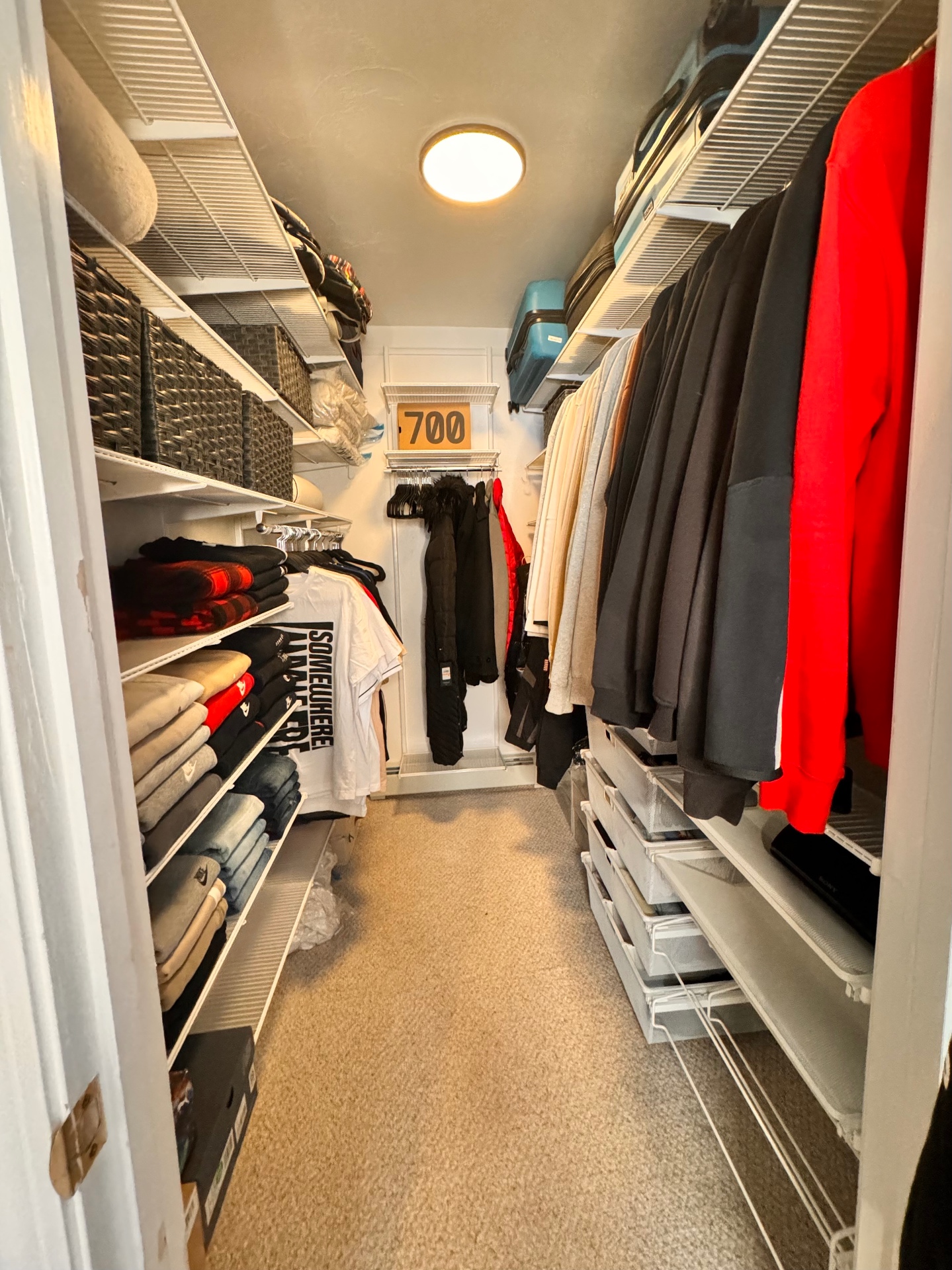 Walk-in closet with folded clothes, hanging garments, and storage baskets.