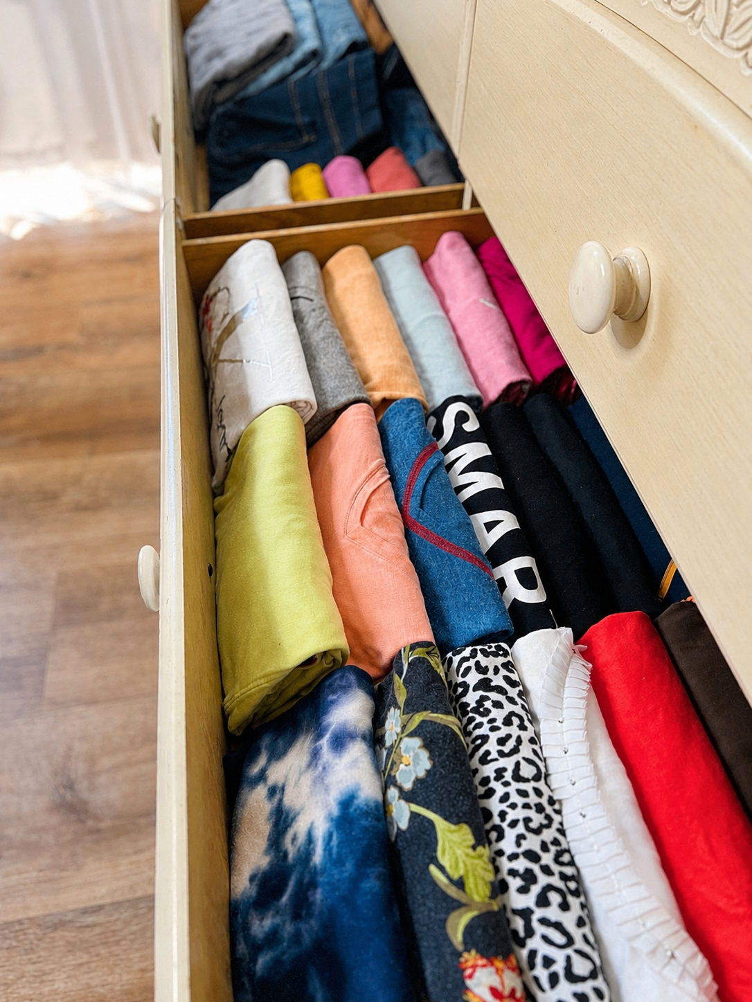 Drawer with t-shirts file-folded and organized by color.